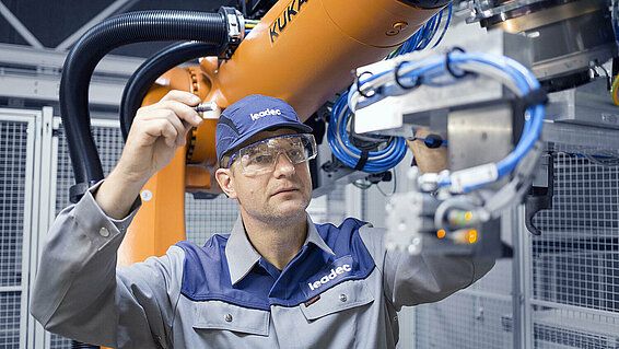 A Leadec employee maintaining a robot in a production.
